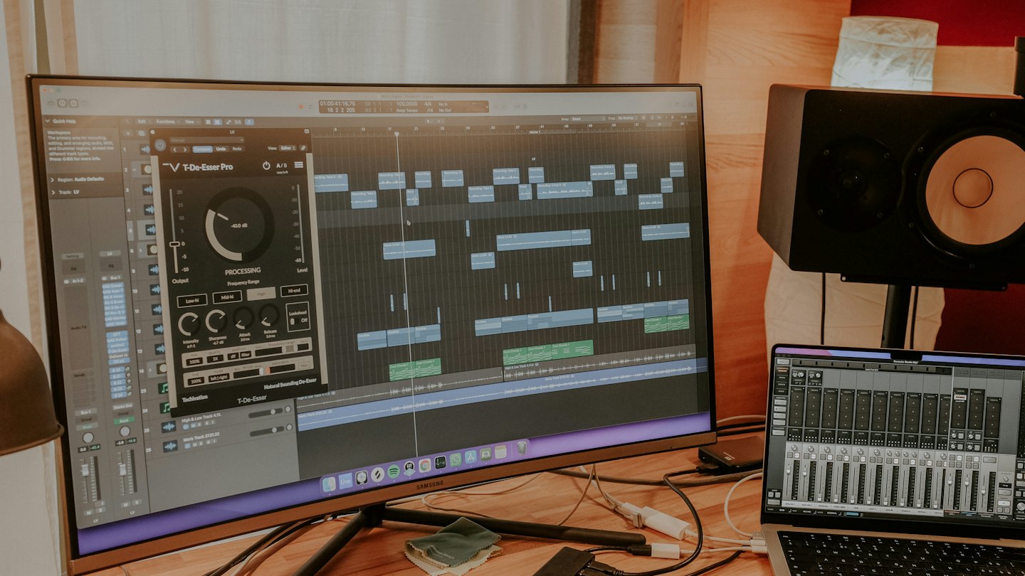 Music production workstation with audio editing software on a curved monitor.